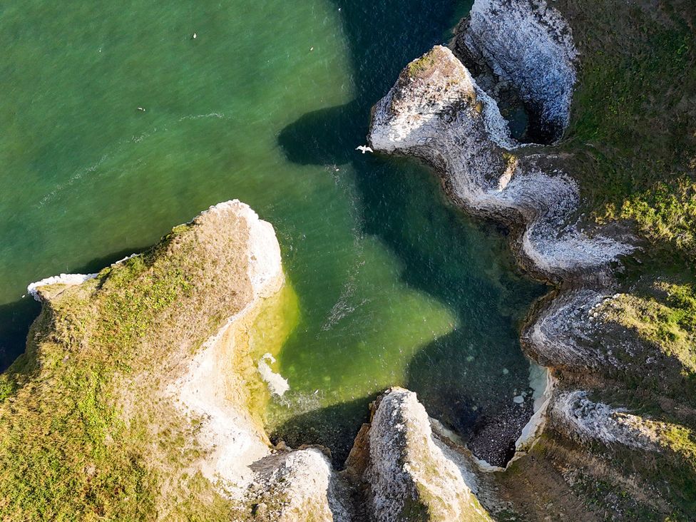 An aerial view of a coastline with rock formations and water at Kittiwake in Flamborough