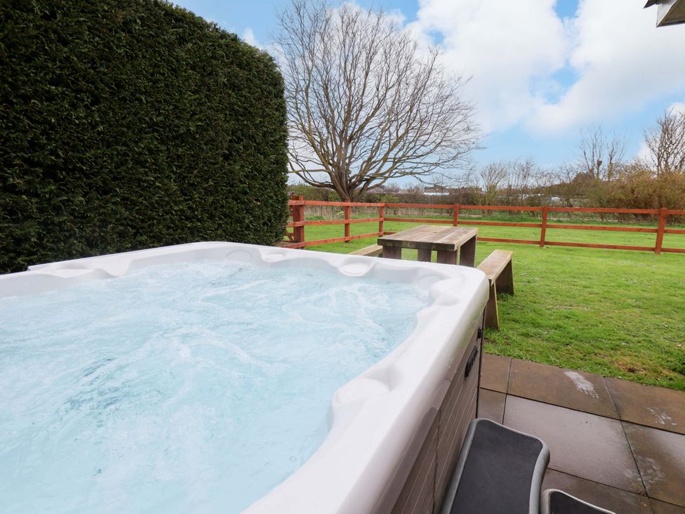 A hot tub with a table and chair in the outdoor area at Kittiwake in Flamborough