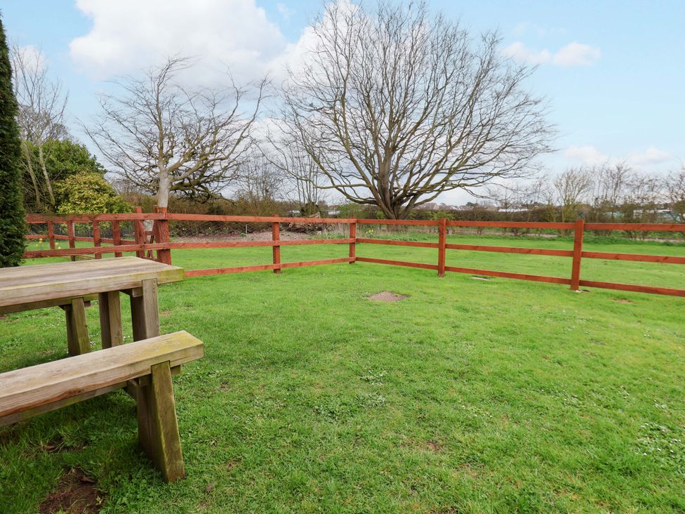 A garden with a wooden table and surrounding fences at Kittiwake in Flamborough