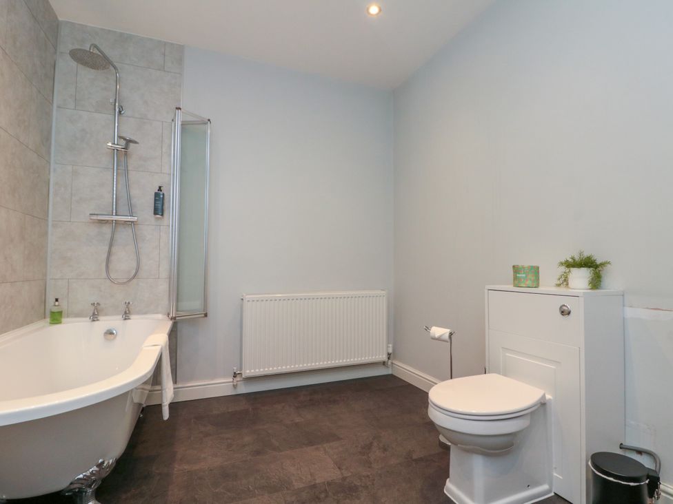 A bathroom with a bathtub, shower, toilet, and radiator at The Pheasantry in Flamborough