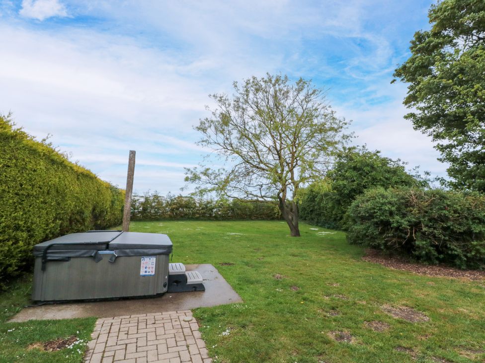 A garden with a hot tub and a pathway at The Pheasantry in Flamborough