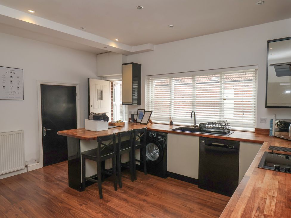 A kitchen with appliances and bar stools at The Pheasantry in Flamborough