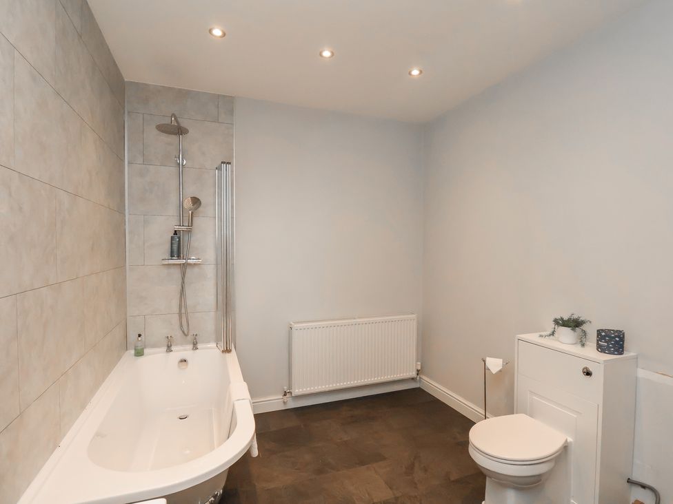 A bathroom with a bathtub, toilet, and shower at The Pheasantry in Flamborough
