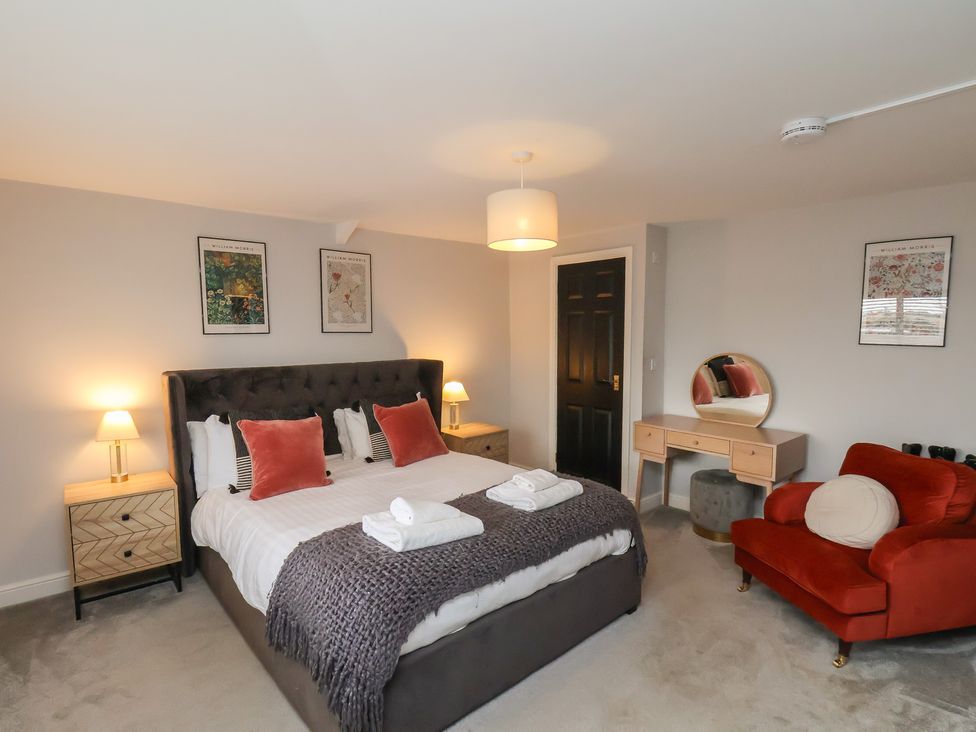 A bedroom with a bed, bedside tables, and chairs at The Pheasantry in Flamborough