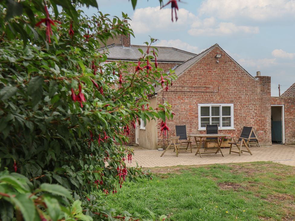 A garden view of a house with a table and chairs at The Pheasantry in Flamborough