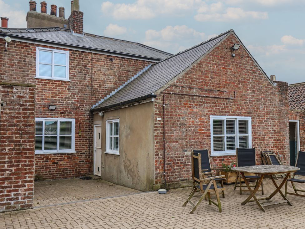 An outdoor area featuring a brick wall, windows, table, and chairs at The Pheasantry in Flamborough