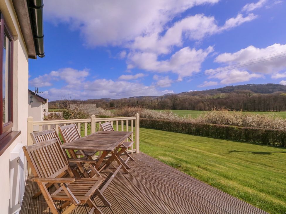 A deck with a table and chairs overlooking a field at Country Cottage in Brecon