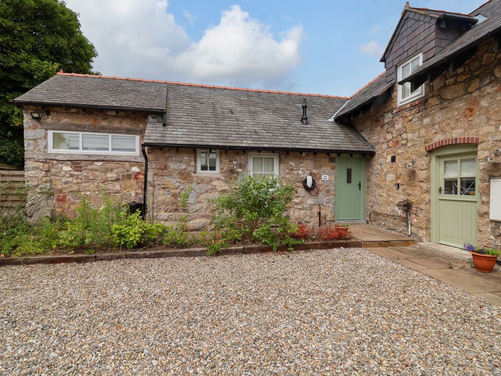 A stone building with a gravel area and plants at The Barn in Tafarn-Y-Gelyn