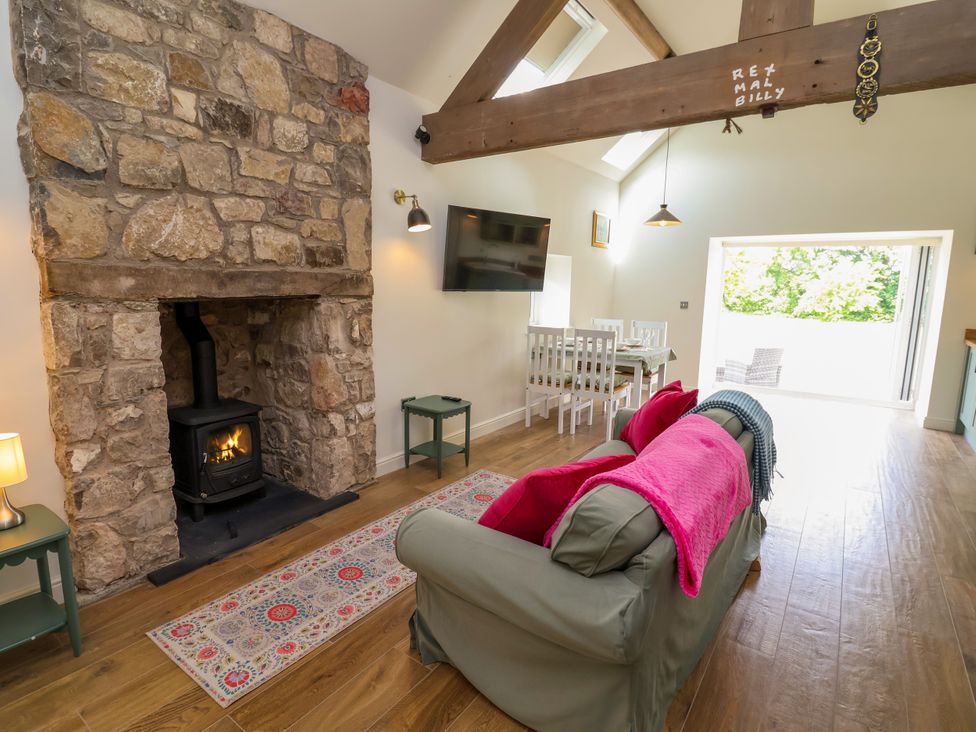 A living room with a stone fireplace and wood stove at The Barn in Tafarn-Y-Gelyn