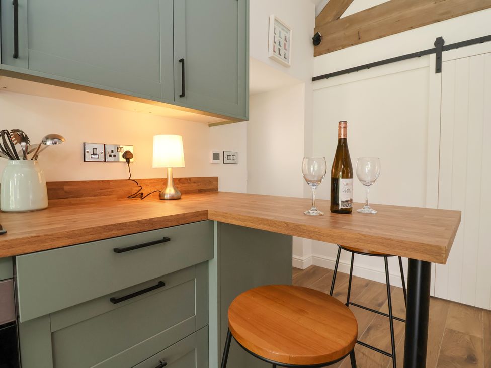 A kitchen with a bar area and wine bottle at The Barn in Tafarn-Y-Gelyn