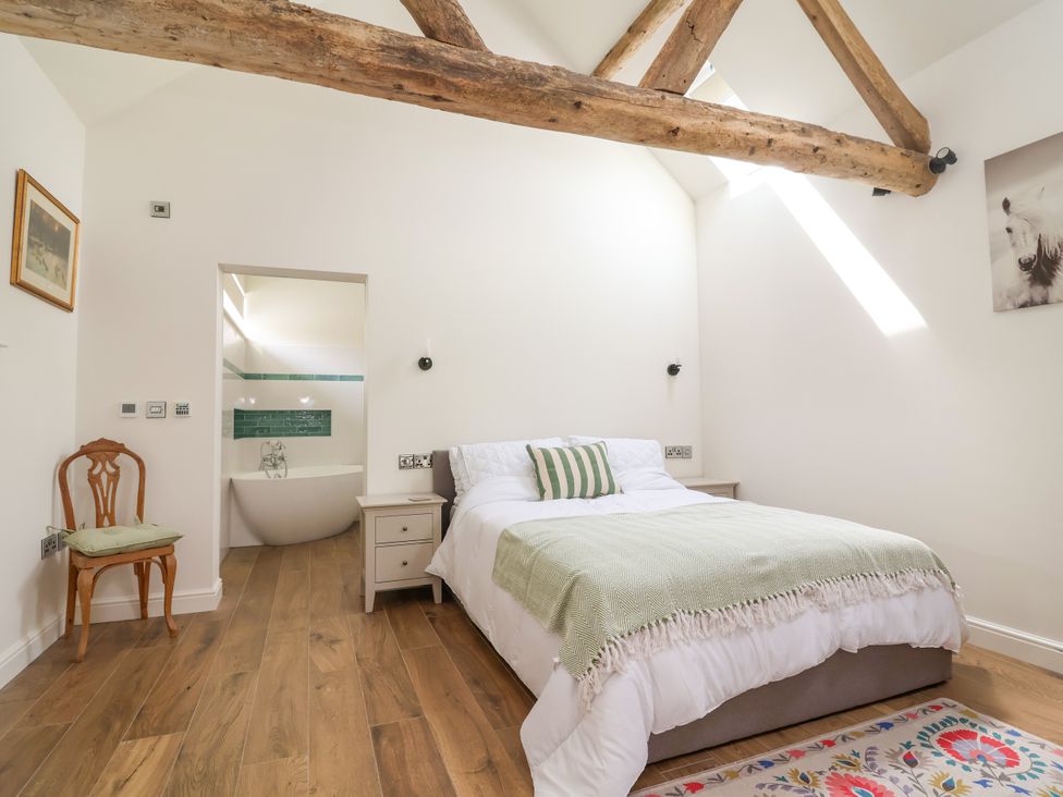 A bedroom with a bed and a bathroom view at The Barn in Tafarn-Y-Gelyn