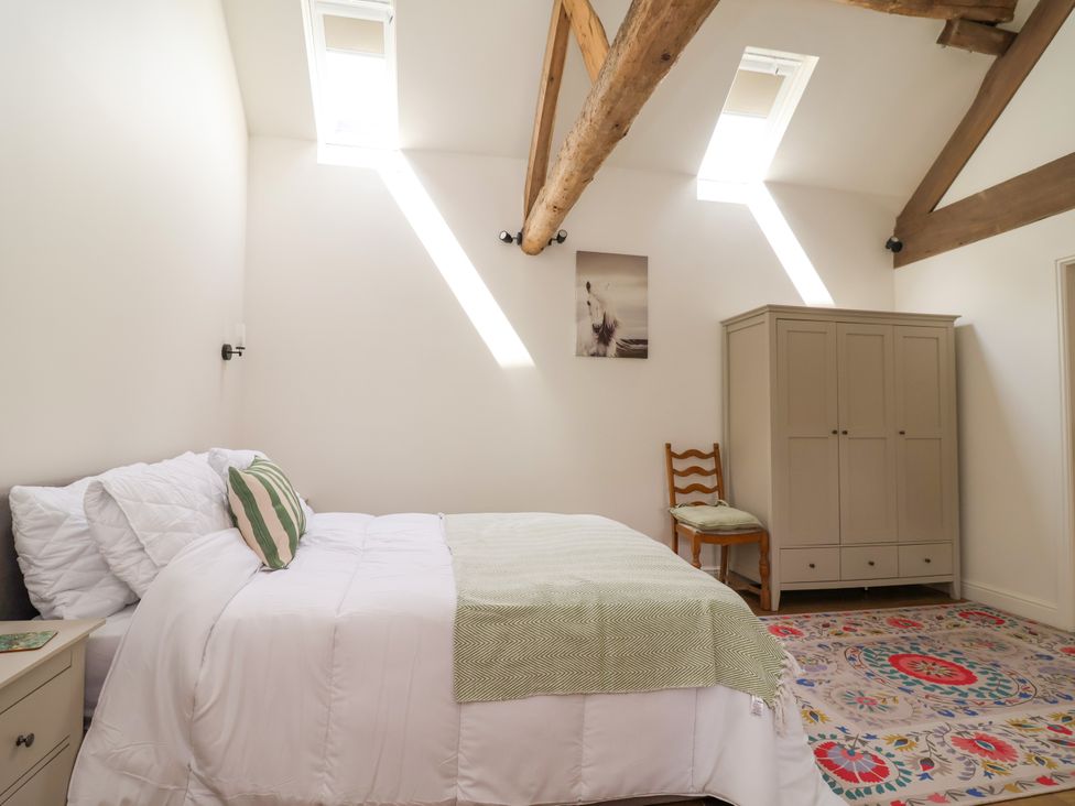 A bedroom with a bed and wardrobe at The Barn Tafarn-Y-Gelyn