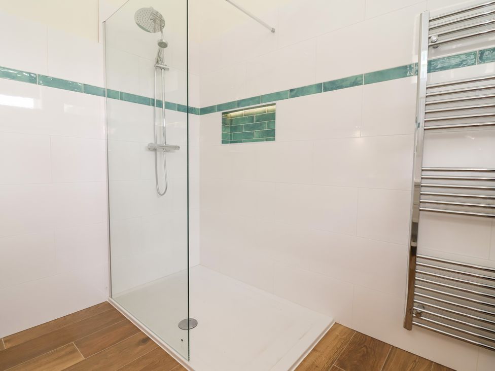 A shower with glass screen and heated towel rail at The Barn Tafarn-Y-Gelyn