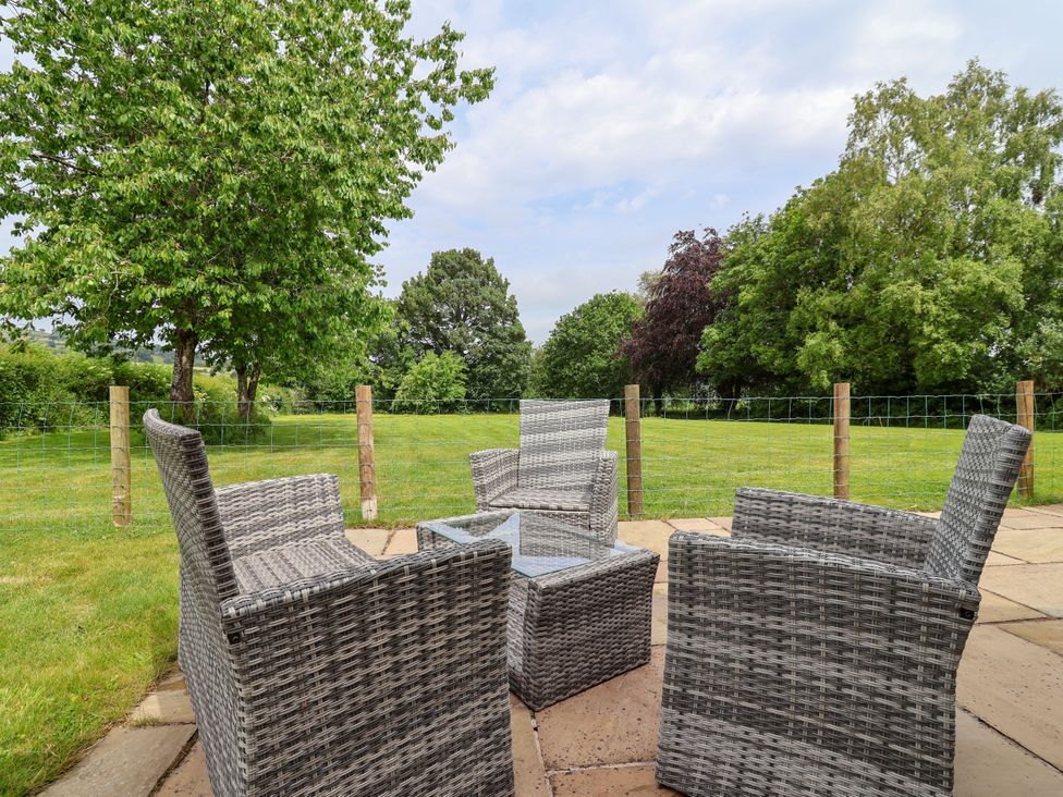 An outdoor area with chairs and a table at The Barn in Tafarn-Y-Gelyn