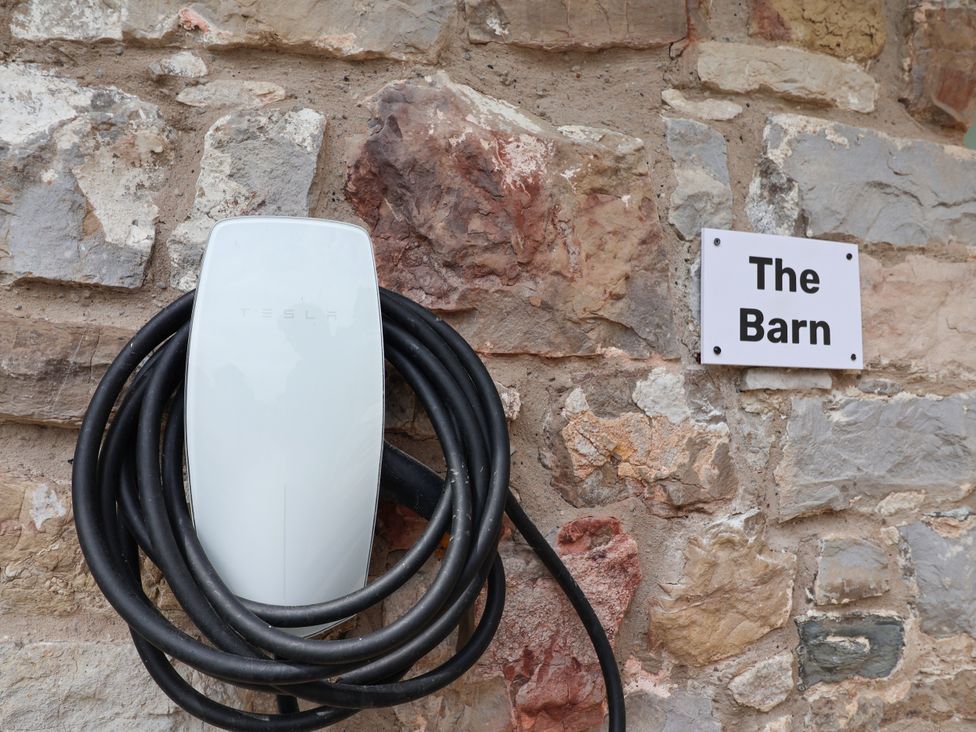 A Tesla charger mounted on a stone wall at The Barn in Tafarn-Y-Gelyn