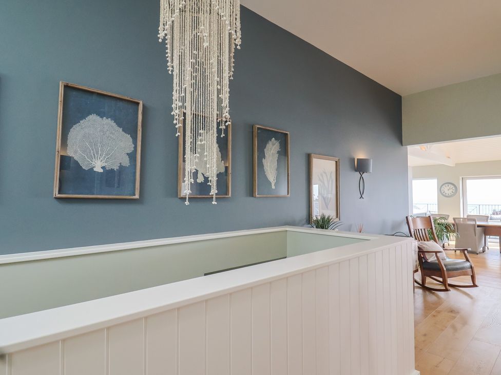 A hallway with wall art and a chandelier at 13 Downside Close in Charmouth