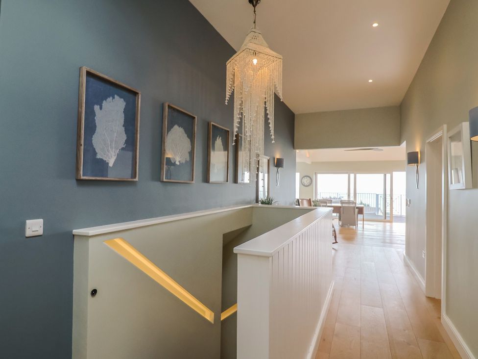 A hallway with a chandelier and wall art at 13 Downside Close in Charmouth