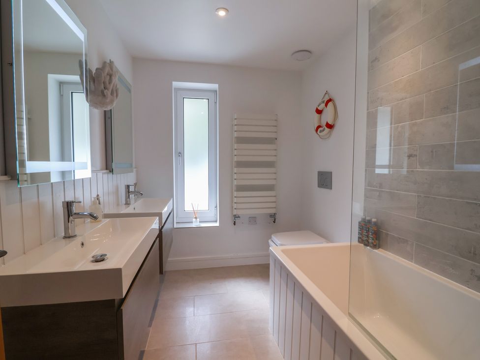 A bathroom with a bath tub and sink at 13 Downside Close Charmouth