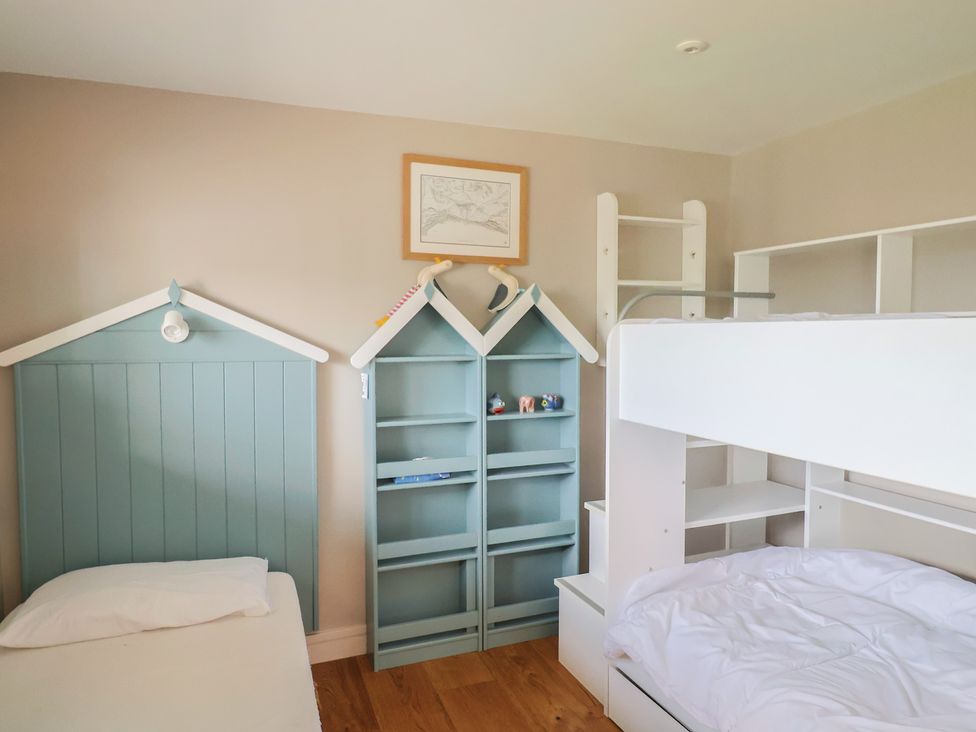A bedroom with bunk beds and a bookshelf at 13 Downside Close in Charmouth