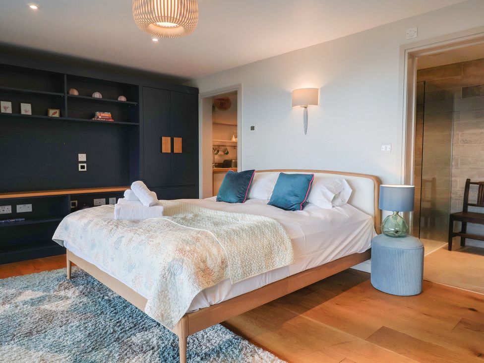 A bedroom with a bed, nightstand, and a shelf at 13 Downside Close in Charmouth