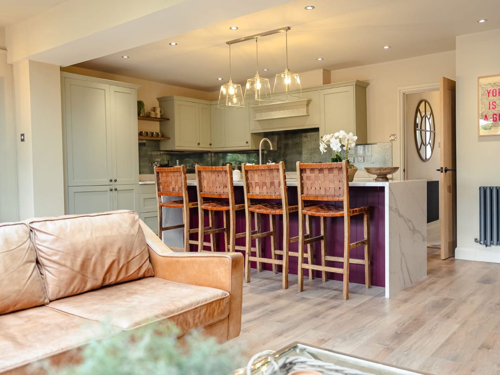 A kitchen with bar stools and cabinets at 3 Olivers View in Brandsby