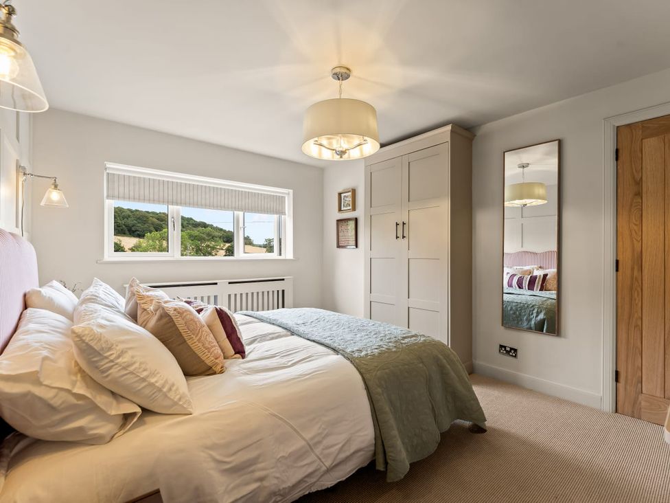 A bedroom with a bed, wardrobe, and window at 3 Olivers View in Brandsby