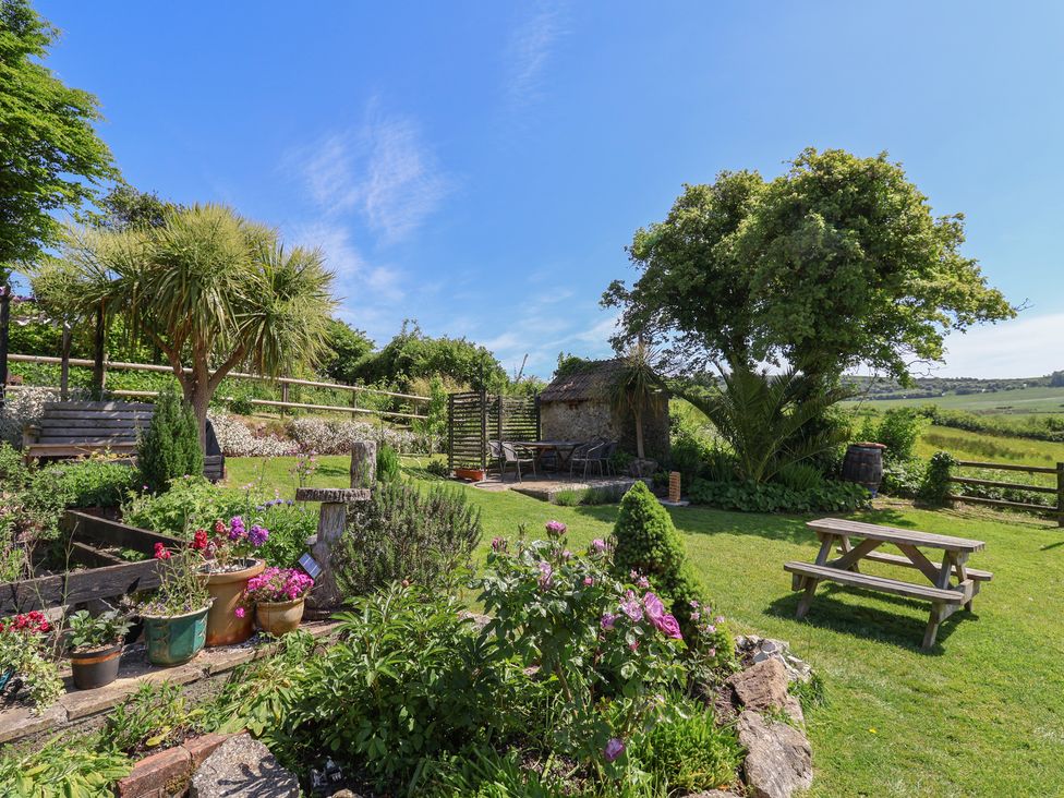 A garden with flower pots seating area picnic table and trees at Eggardon Rest in Askerswell near Bridport