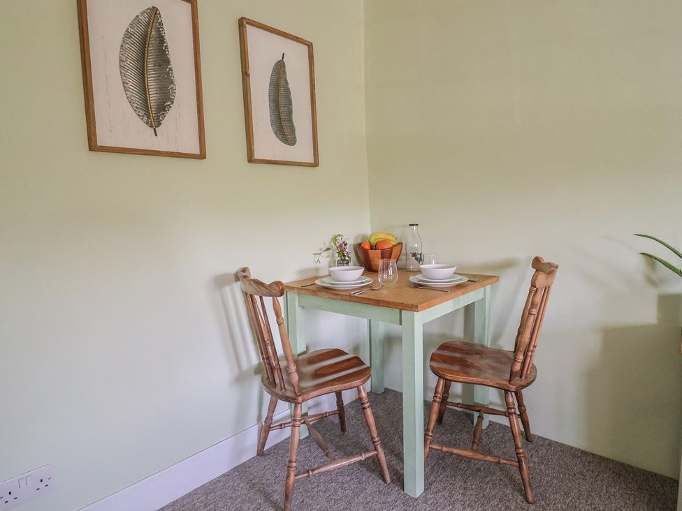 A small dining table with two wooden chairs plates bowls glasses and fruit bowl on it at Eggardon Rest in Askerswell near Bridport