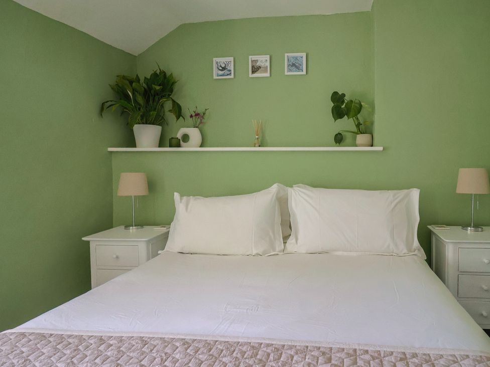 A bedroom with a bed white pillows and bedside tables with lamps at Eggardon Rest in Askerswell near Bridport