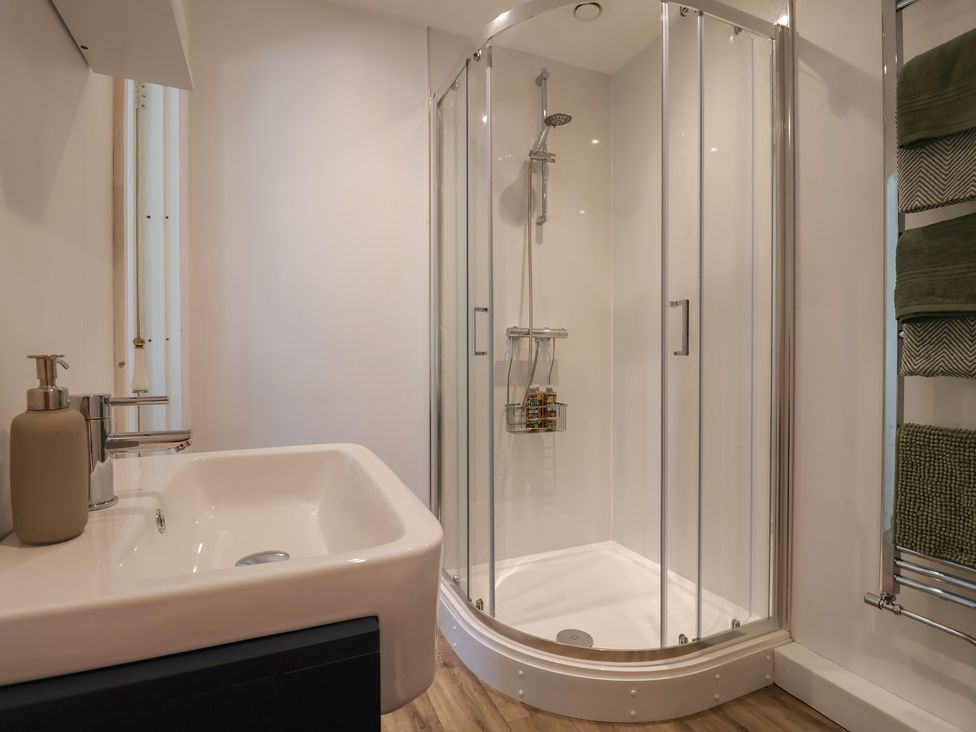 A bathroom with a sink a glass shower enclosure and towels on a rack at Eggardon Rest in Askerswell near Bridport