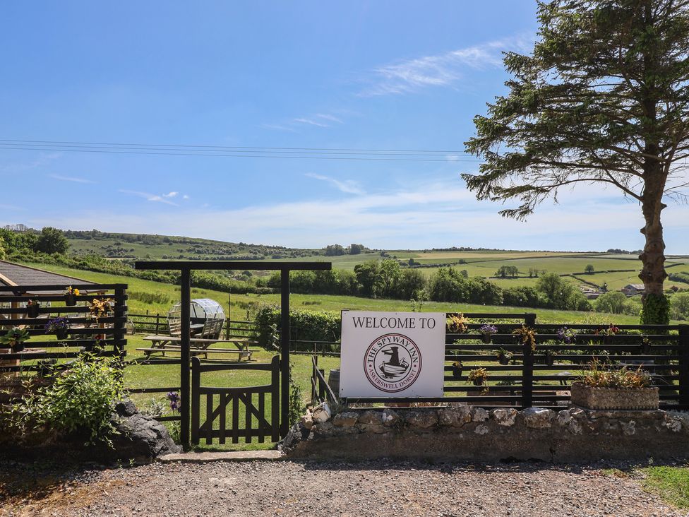 A garden gate with flowers and a welcome sign overlooking fields and hills at Eggardon Rest in Askerswell near Bridport