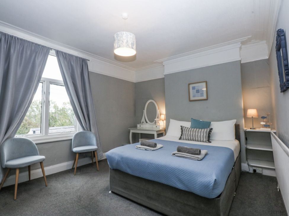 A bedroom with a bed and chairs at Penrhyn Arms Apartment in Llandudno