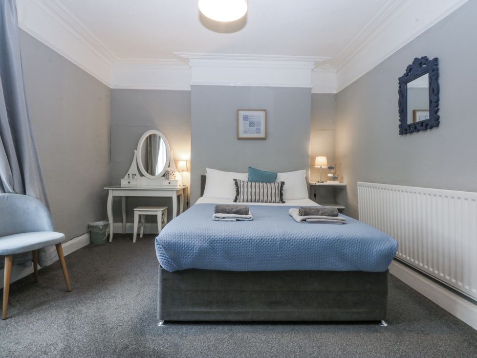 A bedroom with a bed, table, and mirror at Penrhyn Arms Apartment in Llandudno