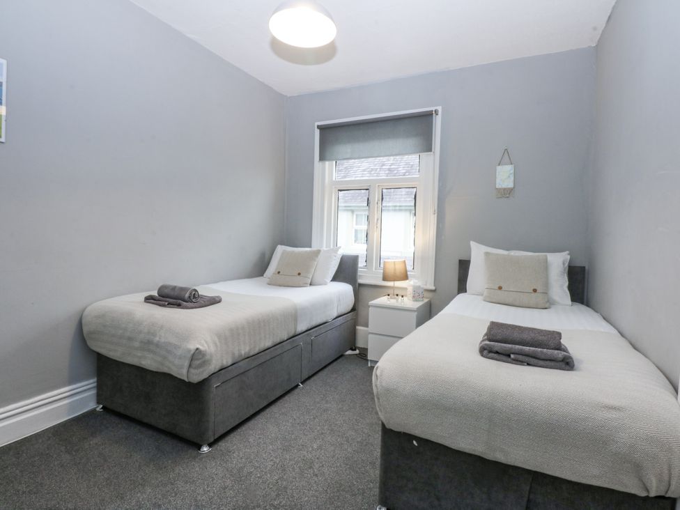 A bedroom with two beds and a nightstand at Penrhyn Arms Apartment in Llandudno