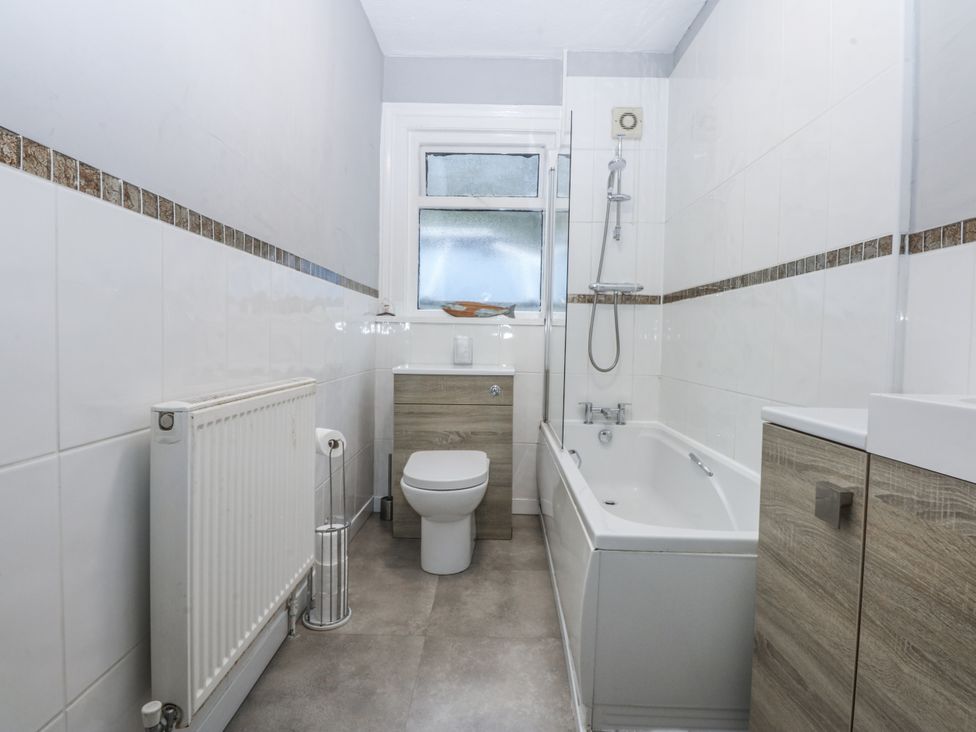 A bathroom with a bath tub a toilet and a sink at Penrhyn Arms Apartment in Llandudno