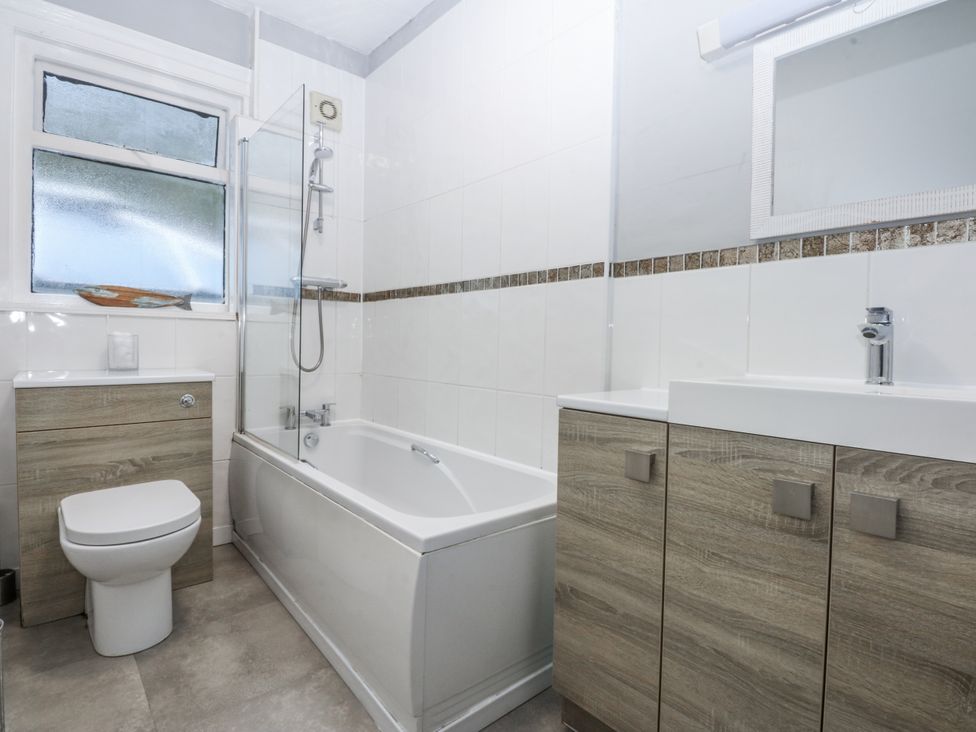 A bathroom with a bathtub, toilet, sink and cabinet at Penrhyn Arms Apartment in Llandudno