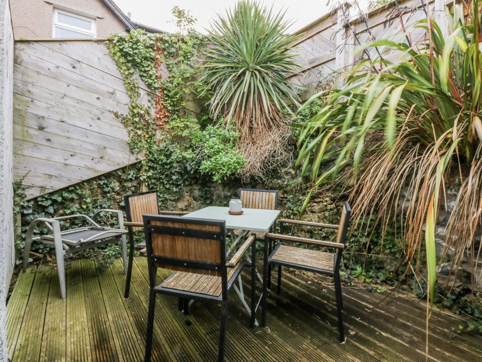 A garden with a table and chairs surrounded by plants at Penrhyn Arms Apartment in Llandudno