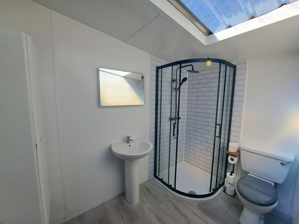A bathroom with a shower enclosure toilet sink and mirror at Capel Park Tyddynod Bach in Llandyfrydog near Llanerchymedd