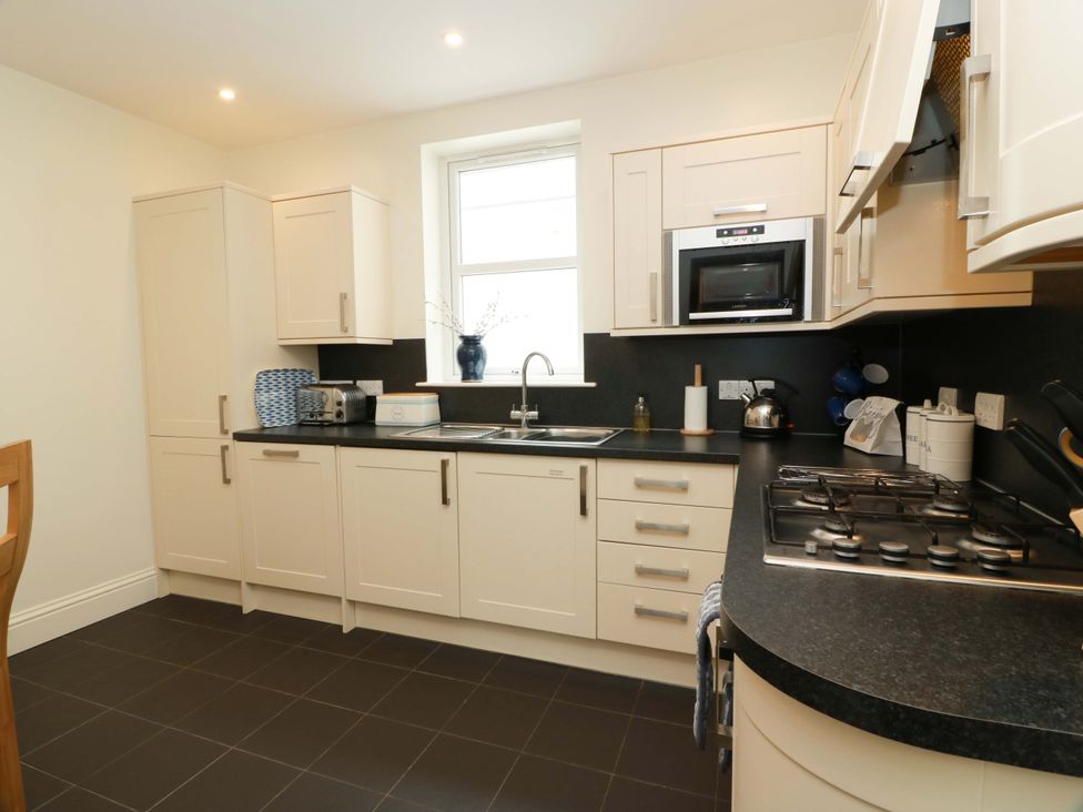 A kitchen with cabinets, sink, gas stove and microwave at Haven Cottage in Kirkcudbright