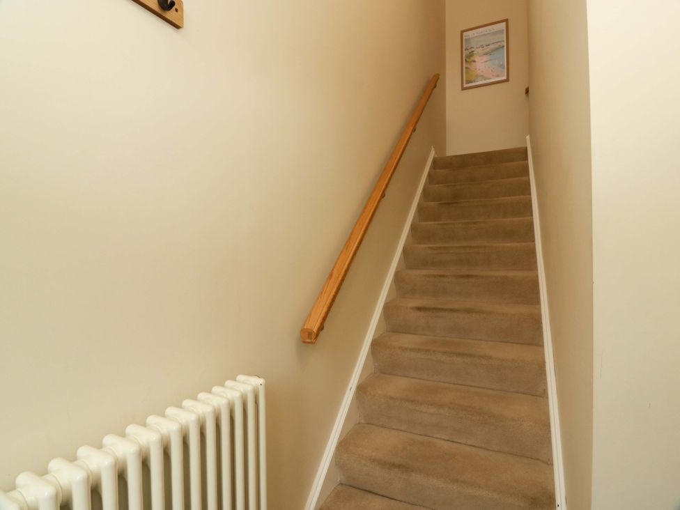 A staircase with a handrail and a radiator at Haven Cottage in Kirkcudbright