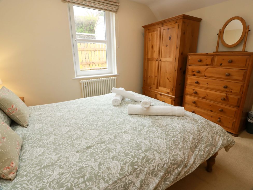 A bedroom with a bed and wooden furniture at Haven Cottage in Kirkcudbright