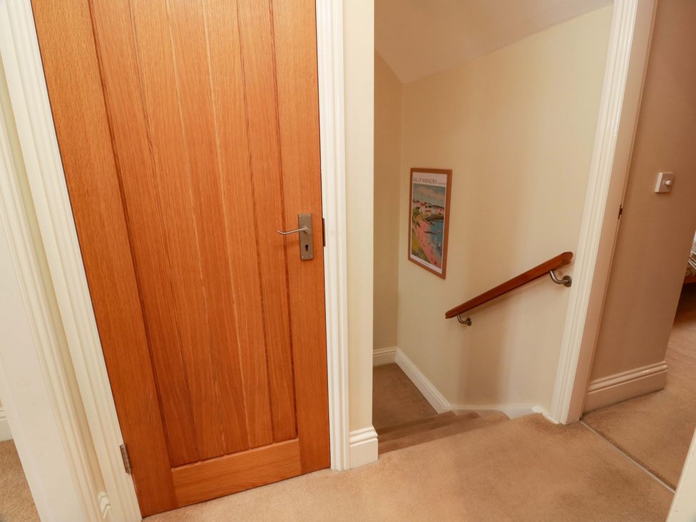 A hallway with a door and stairs at Haven Cottage in Kirkcudbright