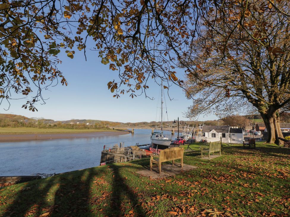 An outdoor area with benches and a river at Haven Cottage in Kirkcudbright