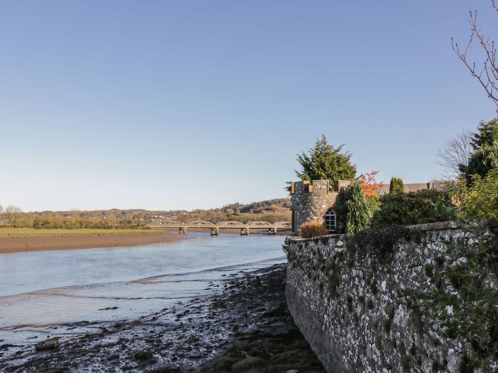 A river with a bridge and a stone wall at Haven Cottage in Kirkcudbright