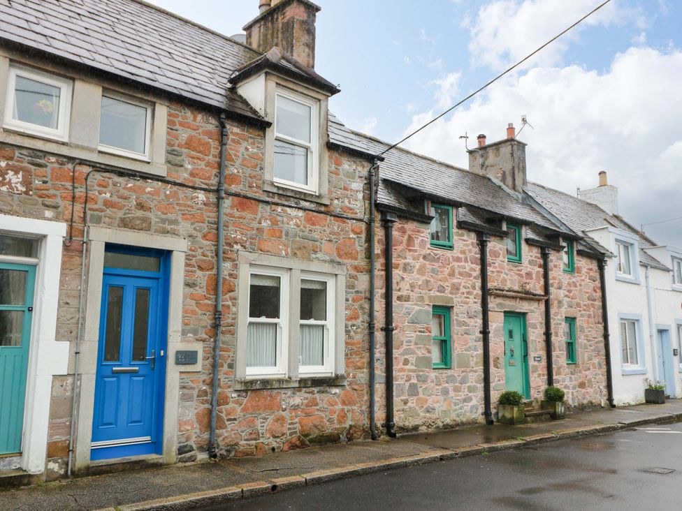 A street view of a stone house with blue and green doors at Haven Cottage Kirkcudbright