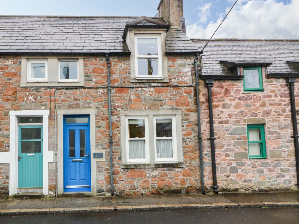 A stone cottage exterior with a blue door and windows at Haven Cottage in Kirkcudbright