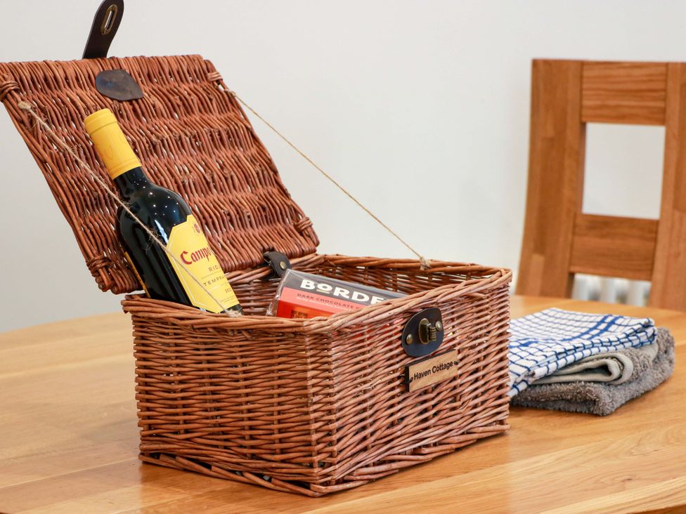 A wicker basket with wine and chocolate on a table at Haven Cottage in Kirkcudbright