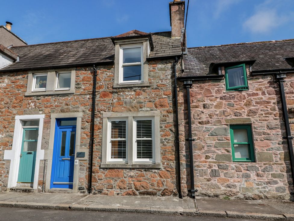 An outdoor view of a stone house with blue and green doors at Haven Cottage in Kirkcudbright