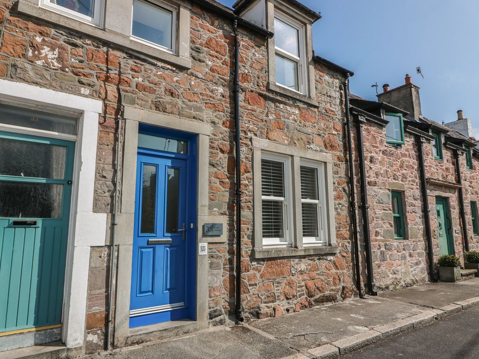 An outdoor view of stone houses with blue and green doors at Haven Cottage in Kirkcudbright