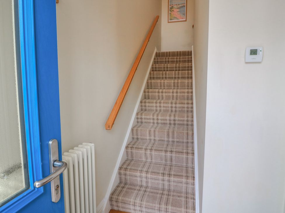 A hallway with stairs leading to an upper level at Haven Cottage in Kirkcudbright
